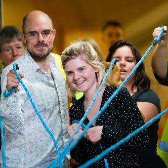 Adults working together in an activity holding ropes joined together
